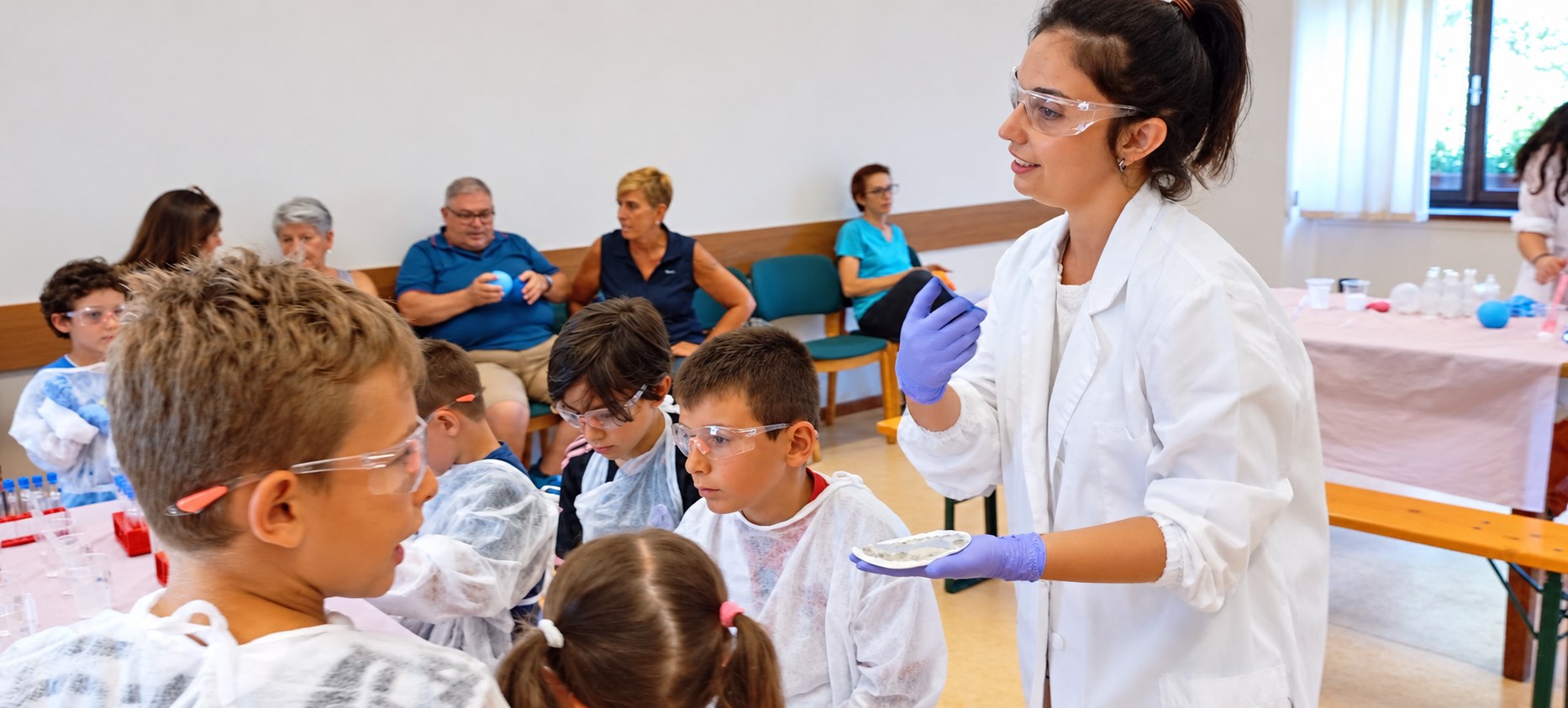 Andrea e un gruppo di bambini con occhiali protettivi durante un laboratorio scientifico